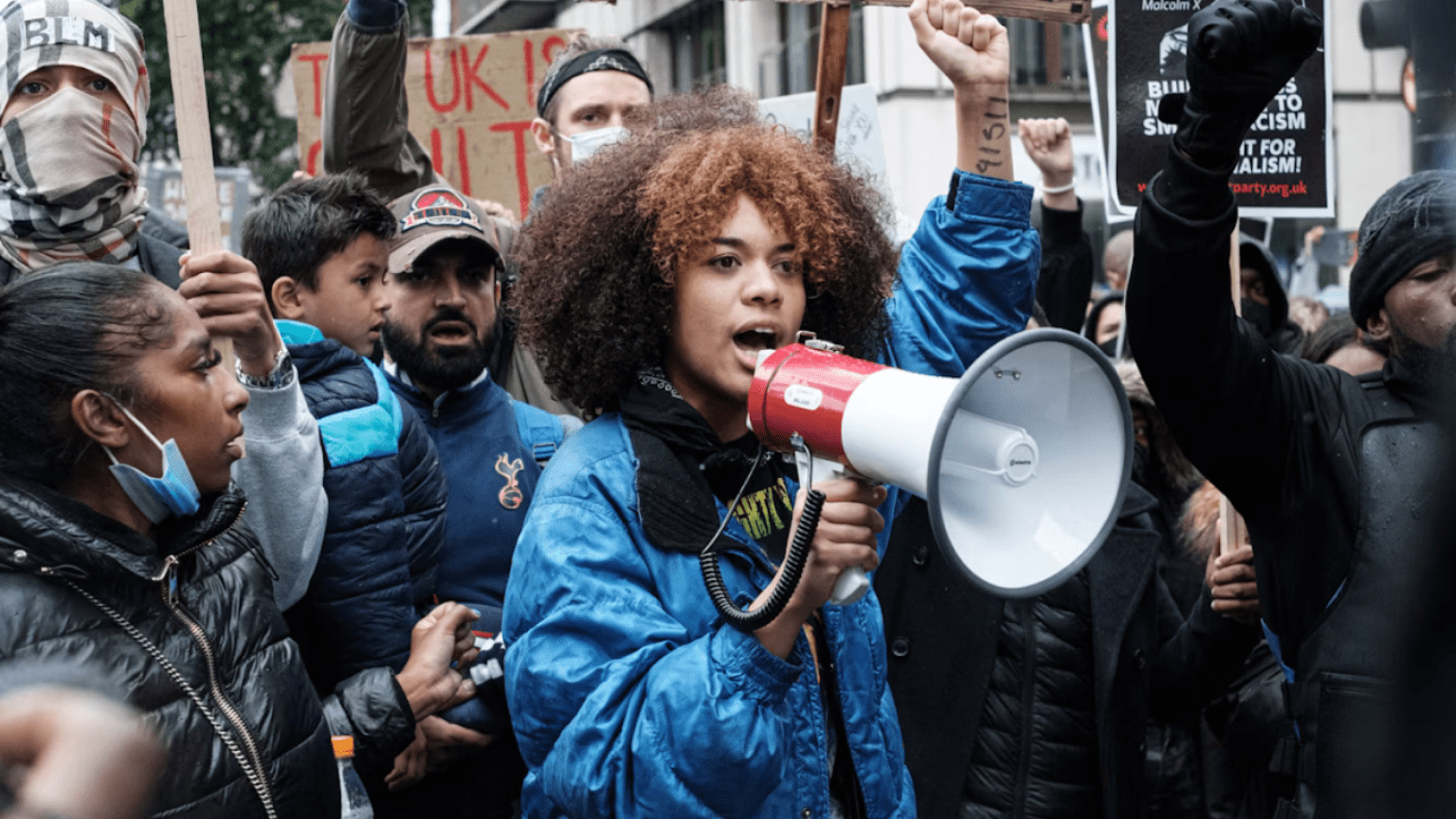 Demonstration med kvinna med megafon i fokus. 