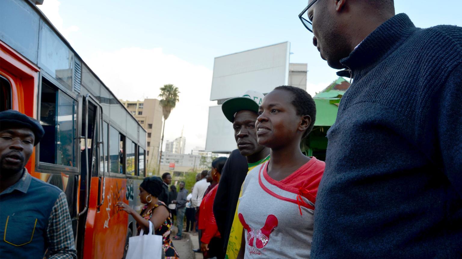 Fyra personer står och pratar på en stimmig busshållplats i Nairobi. I centrum står Sara Nyokabi 
