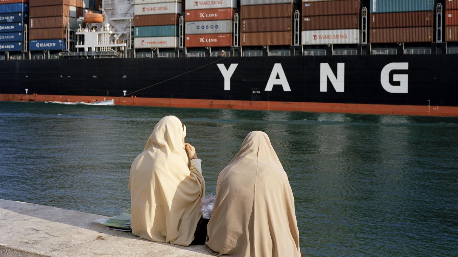 Två kvinnor tittar på ett containerfartyg i Suezkanalen.