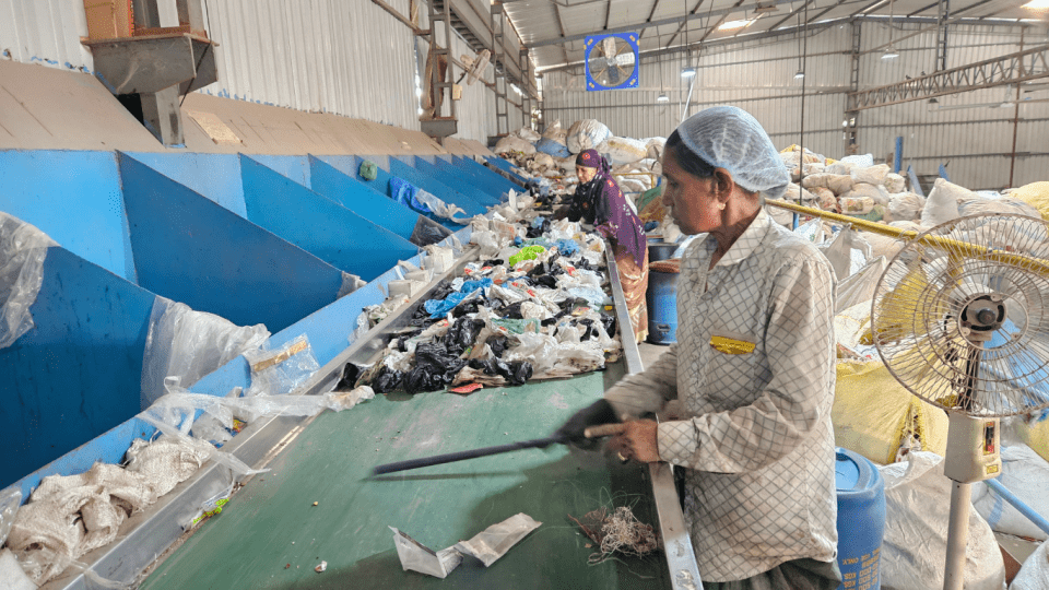 Kvinna sopsorterar på fabrik i Indien. 